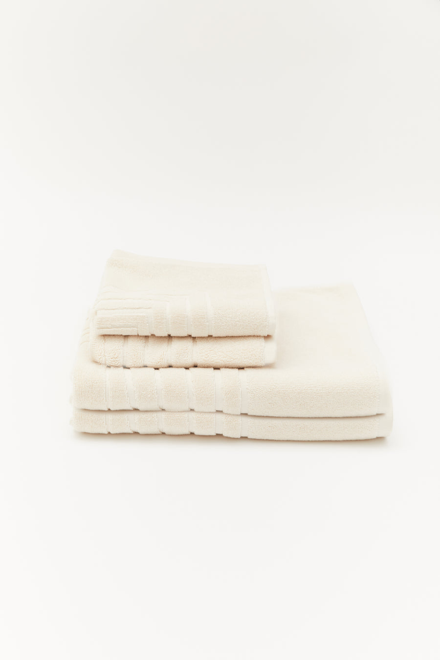 alt="Top-down view of folded Laze Res organic cotton bath set with embossed detailing on neutral surface"