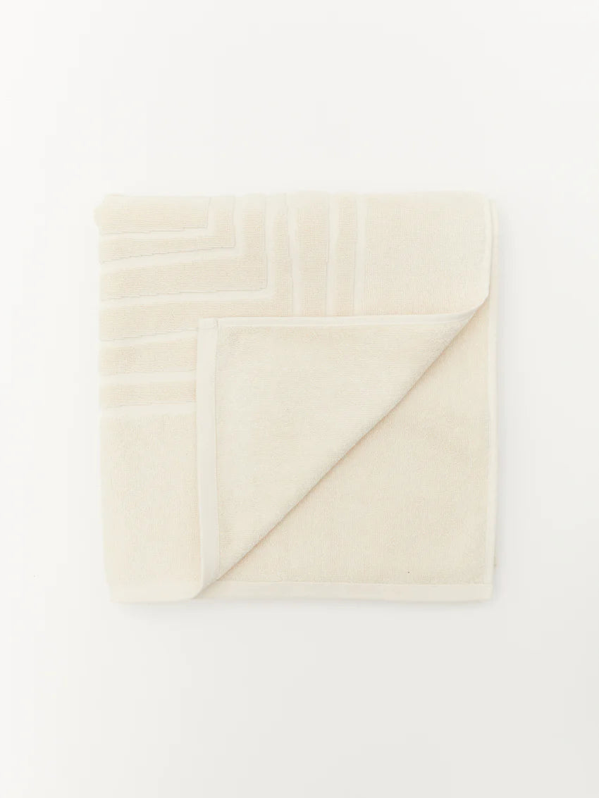 alt="Laze Res organic cotton bath towel with embossed calming line motif, folded neatly"